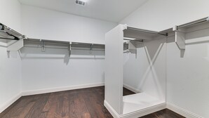 A room with white walls, dark wooden flooring, and built-in closet storage with metal rods. - Near Lake & Family Fun! Spacious Oak Point Home (Little Elm)