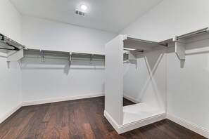 A room with white walls, dark wooden flooring, and built-in closet storage with metal rods. - Near Lake & Family Fun! Spacious Oak Point Home (Little Elm)