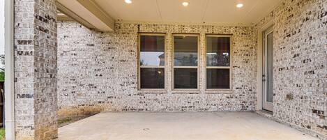 A covered patio area with brick walls and a concrete floor.