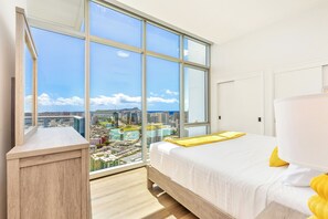 Ein Schlafzimmer mit großem Fenster, einem Bett und Blick auf eine Stadtlandschaft.