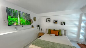 Ein Schlafzimmer mit einem Bett, einem an der Wand montierten Fernseher und drei gerahmten Bildern.