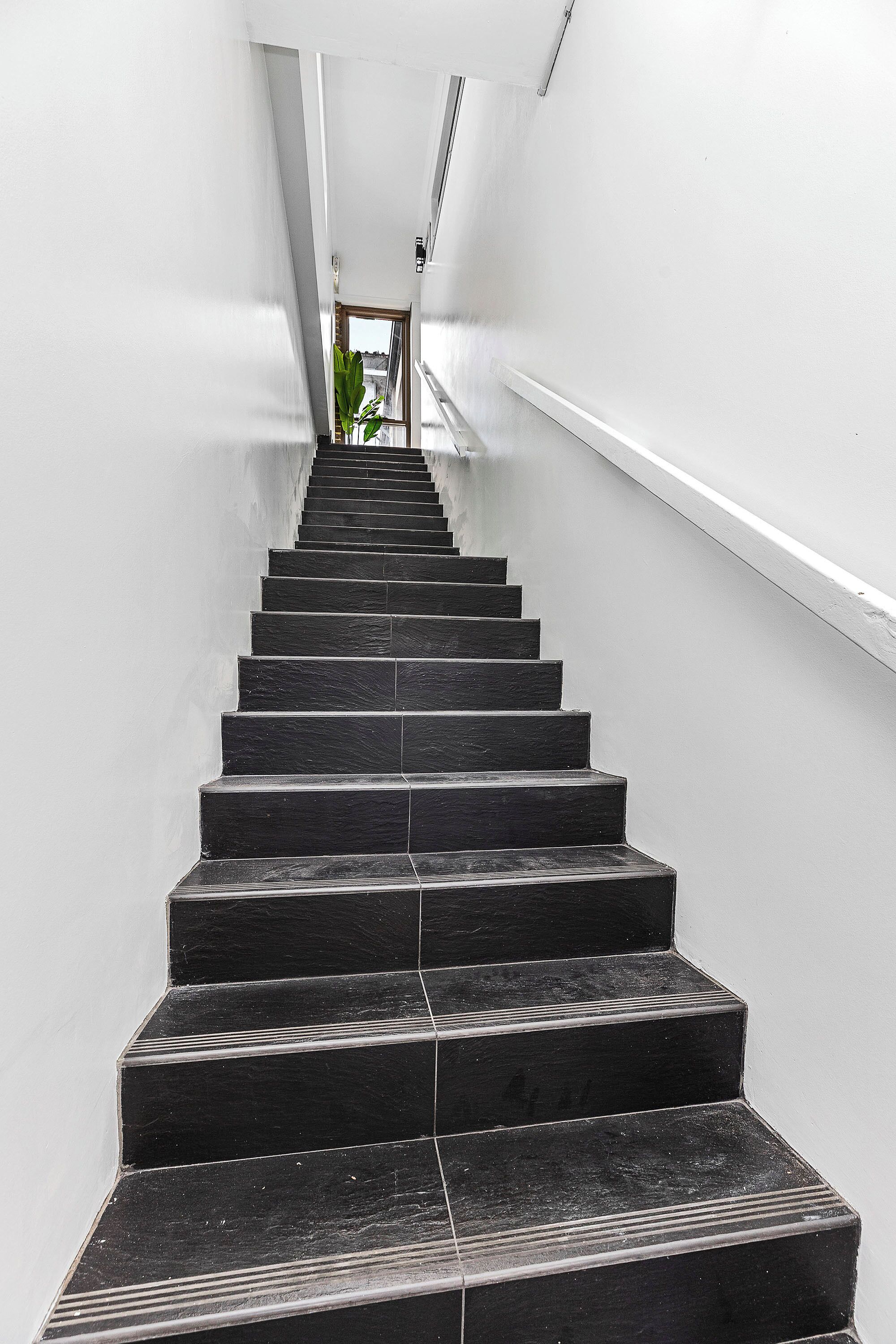 A staircase with a handrail on one side and a door at the top.