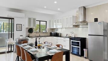 A modern kitchen with a dining area, stainless steel appliances, and a large window.