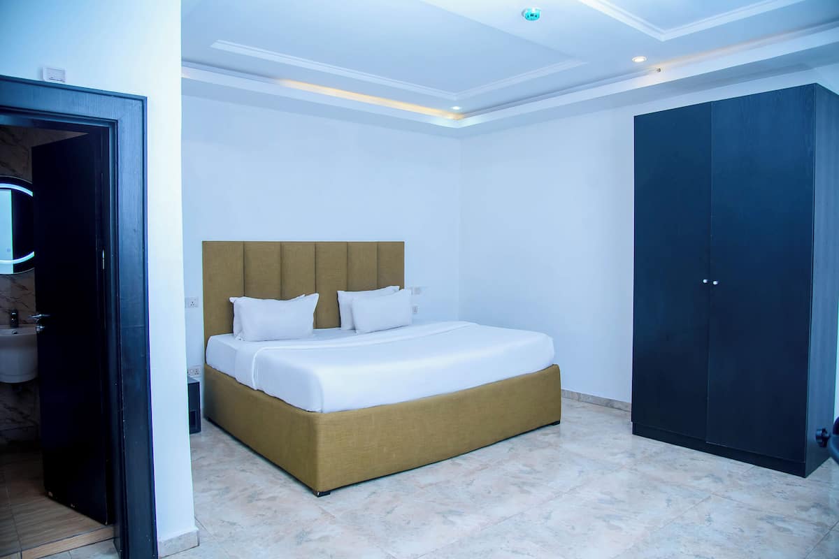 Ein Schlafzimmer mit Bett, Schrank und einem durch eine offene Tür einsehbaren Badezimmer.