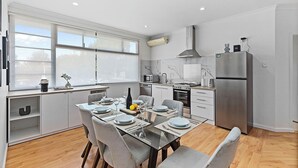 Eine moderne Küche mit Essbereich, großen Fenstern und einem Edelstahl-Kühlschrank.