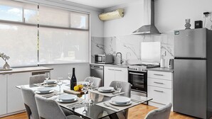 Eine moderne Küche mit Essbereich, ausgestattet mit integriertem Backofen, Mikrowelle und einem Edelstahl-Kühlschrank.