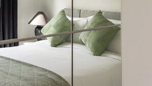 A hotel room with a bed, a lamp, a framed picture on the wall, and a window with curtains. - One Bedroom Apartment in West Kensington (London)