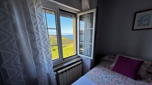 Ein Schlafzimmer mit einem Bett, einem Vorhangfenster und einer Heizung.