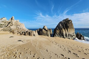 Ein Strand mit großen Felsformationen und Fußabdrücken im Sand.