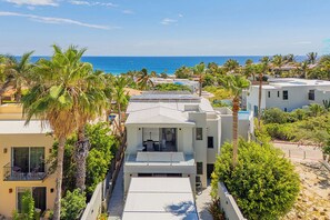 A modern residential building with a balcony overlooking a coastal area. - Walk to Beach Modern Oceanview Villa w/ 2 Pools, Hot Tub & Concierge Cabo (Cabo San Lucas)