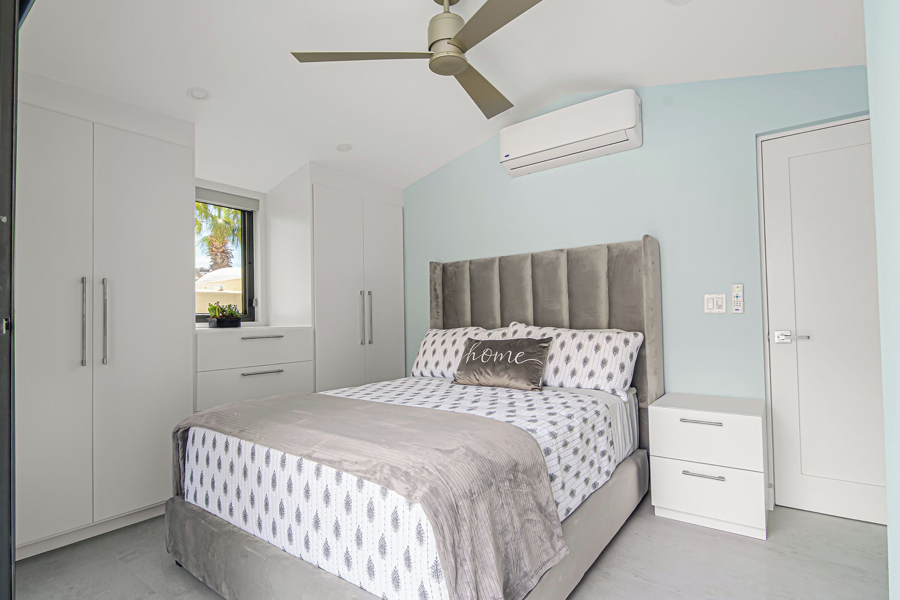 Une chambre à coucher comprenant un lit, une table de chevet, une armoire et un ventilateur de plafond.