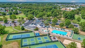 Eine Vogelperspektive auf eine Wohngegend mit einem großen Haus, Tennisplätzen und einem Swimmingpool.