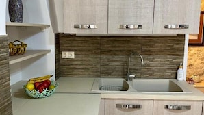 A kitchen with light wood cabinets, a sink, and a fruit bowl on the counter. - Casa Joanna Old Town Rethymno (Rethymno)