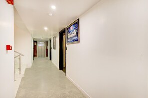 A hallway with a fire alarm, a framed picture, and doors leading to rooms. - Deluxe Hotel Uppal International (New Delhi)