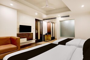 A hotel room with a TV, two beds, a sofa, a wardrobe, and a window. - Deluxe Hotel Uppal International (New Delhi)