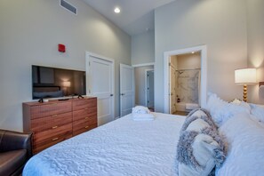 A hotel room with a bed, a TV, a dresser, and a bathroom visible through an open door.