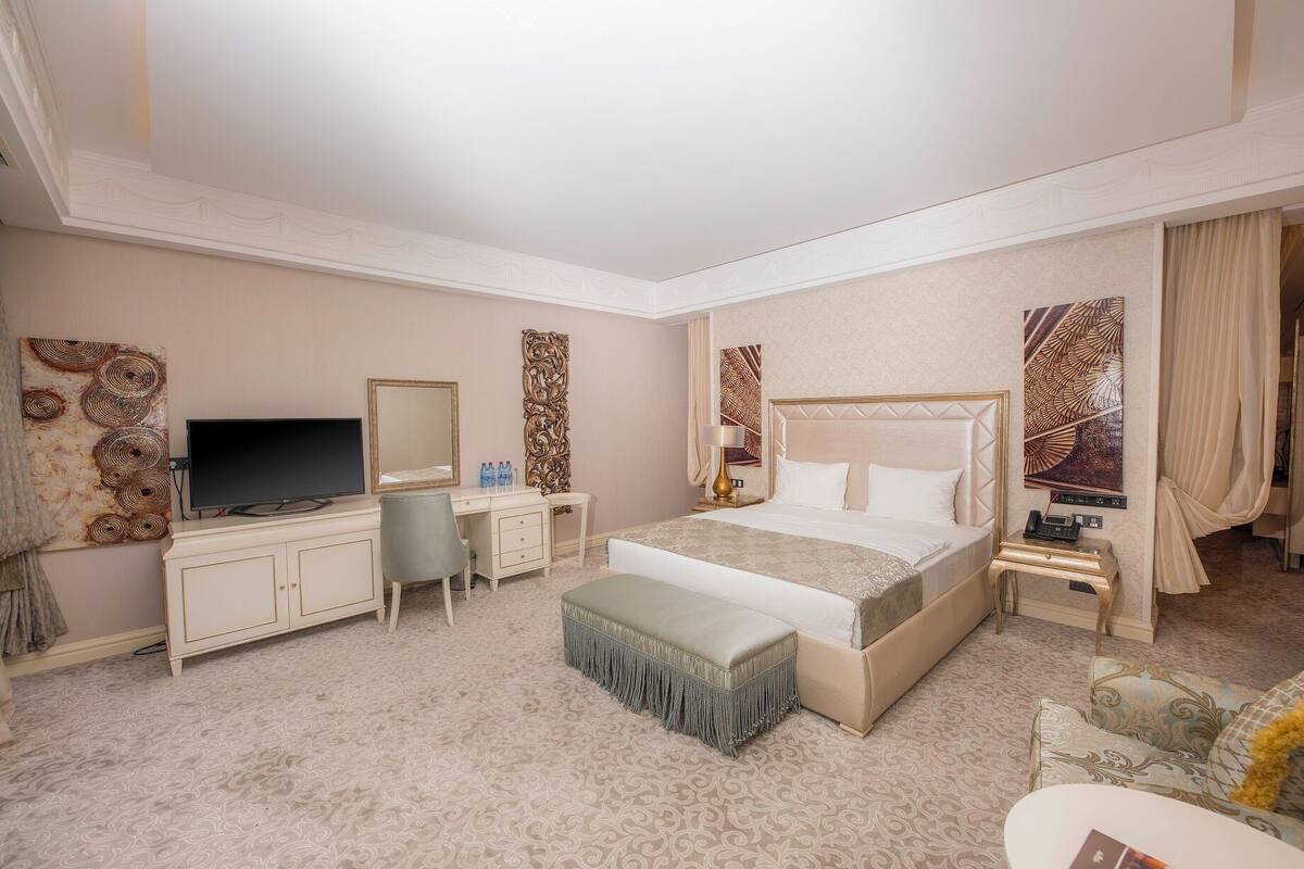 Een hotelkamer met een bed, bureau, televisie en een grote spiegel.