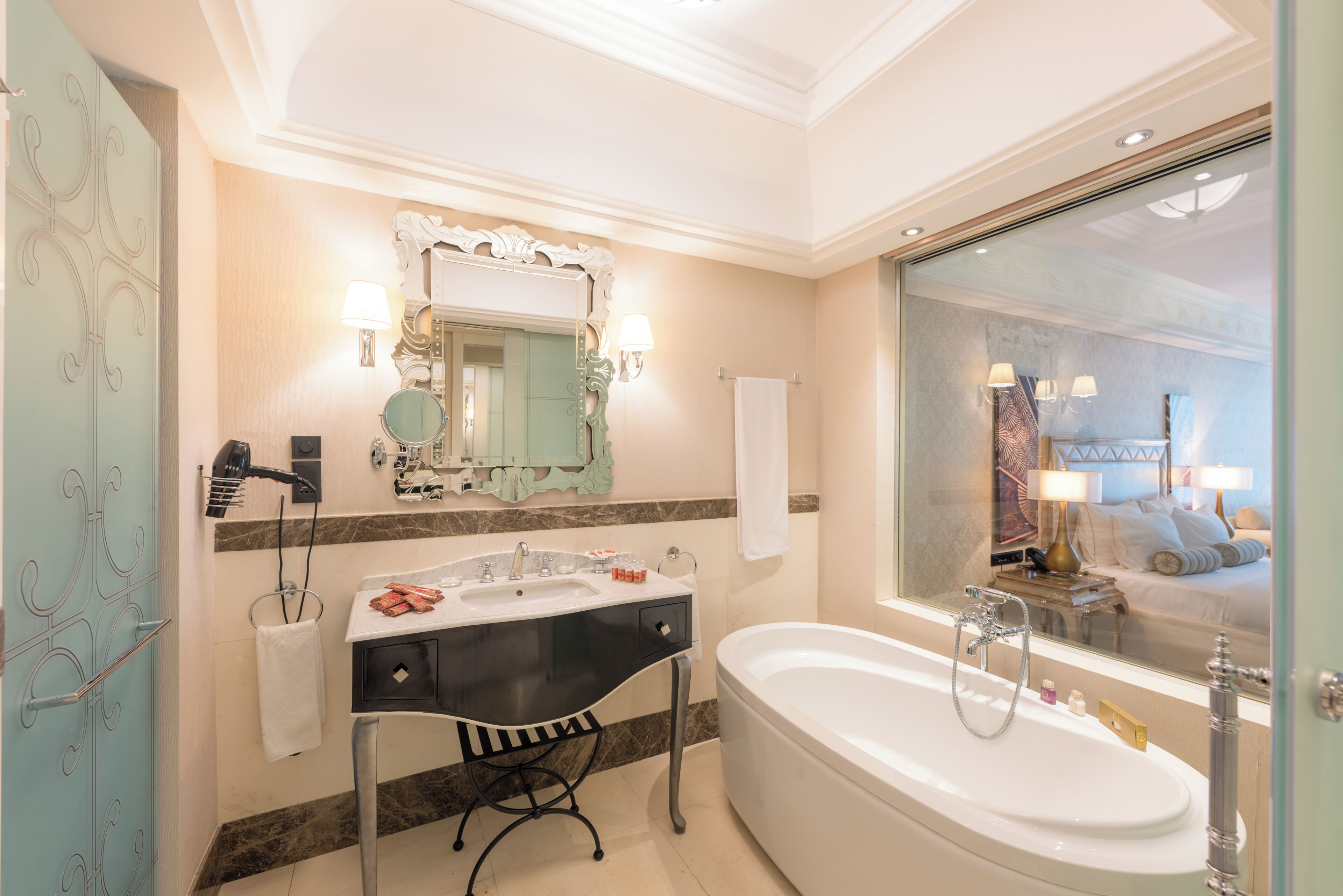 A bathroom with a large bathtub, a vanity with a mirror, and a towel rack.