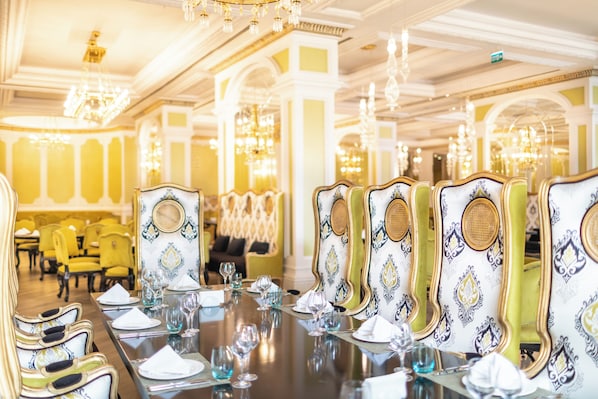 A formal dining room with a long table set for multiple guests, ornate chairs, and chandeliers. - Quba Palace Hotel & Golf Resort (Quba)