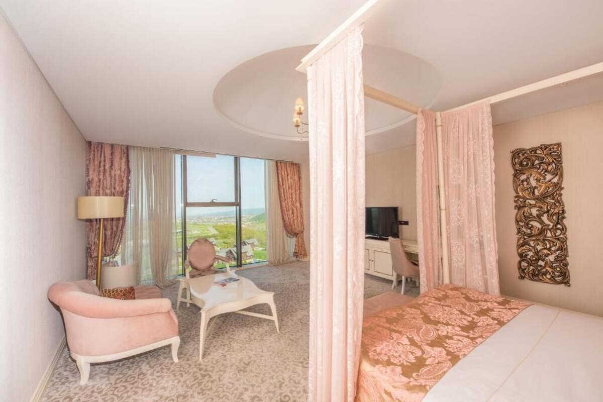 Een hotelkamer met een groot bed, een bureau, een stoel, een klein tafeltje en uitzicht op het landschap.