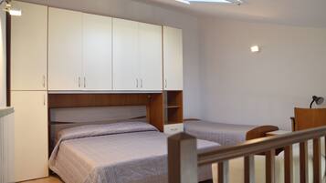 Een slaapkamer met twee enkele bedden, een houten bureau en een witte kast.
