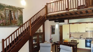 Eine Treppe führt zu einem Erker, einem Essbereich mit Stühlen, einer Küche mit Schränken und einem Heizkörper.