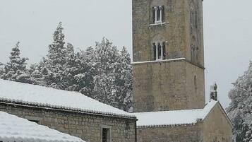 A stone building with a tower, snow-covered trees, and a clear sky.
