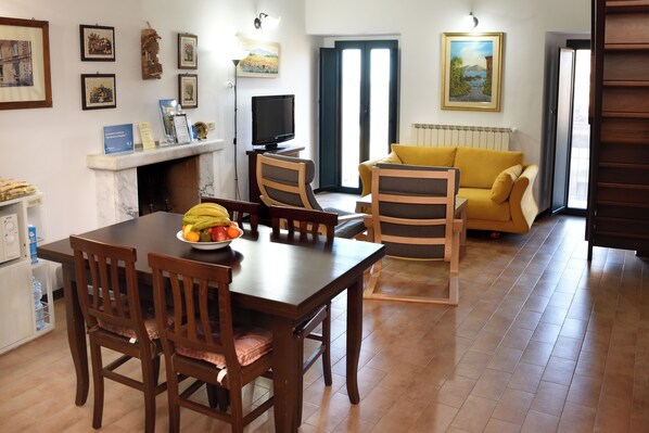A dining area with a table, chairs, a television, and a sofa.