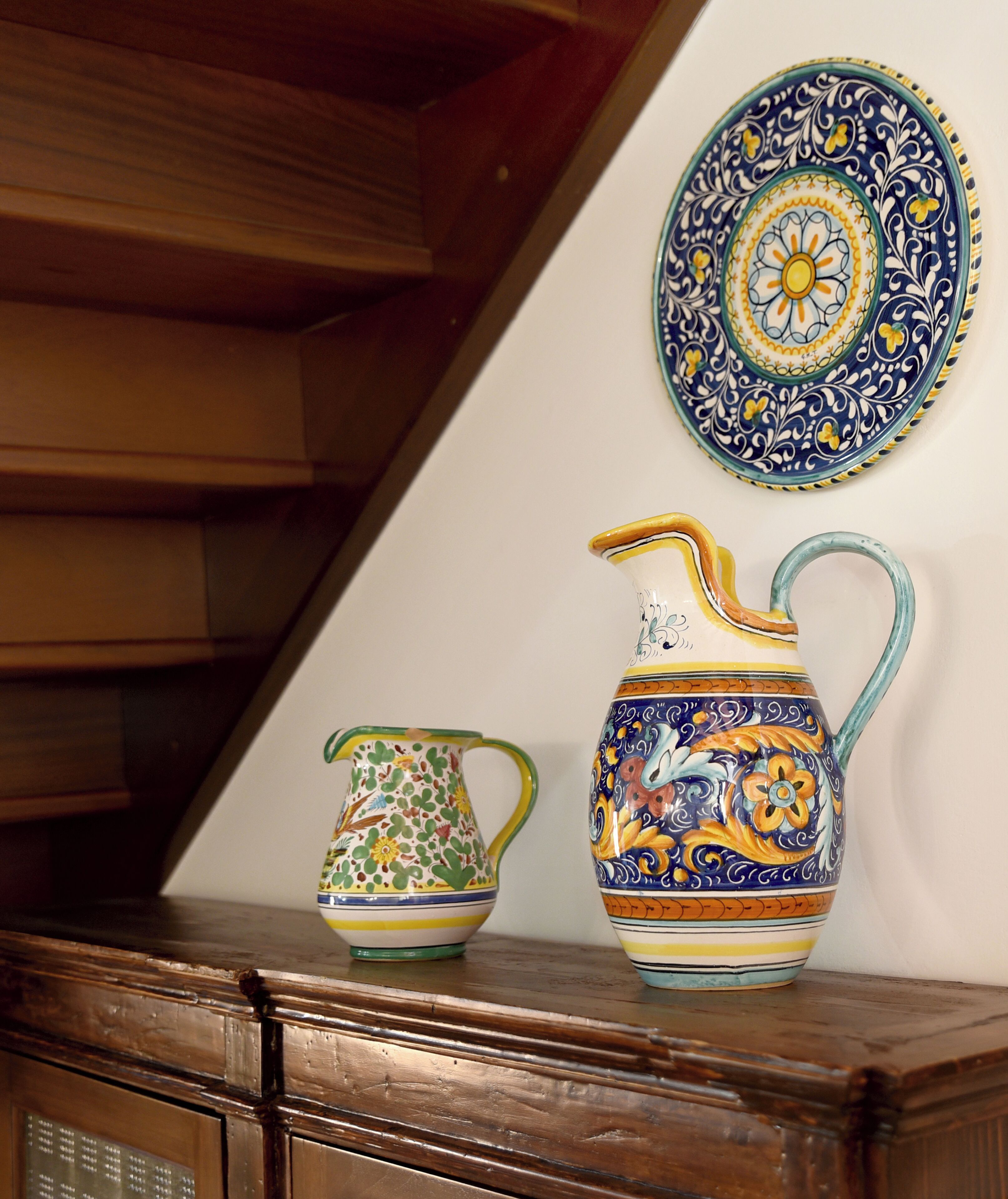 A wooden cabinet with two ceramic pitchers on top.