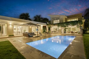 Une maison moderne dotée d’une piscine, d’un espace salon extérieur et d’un patio couvert.