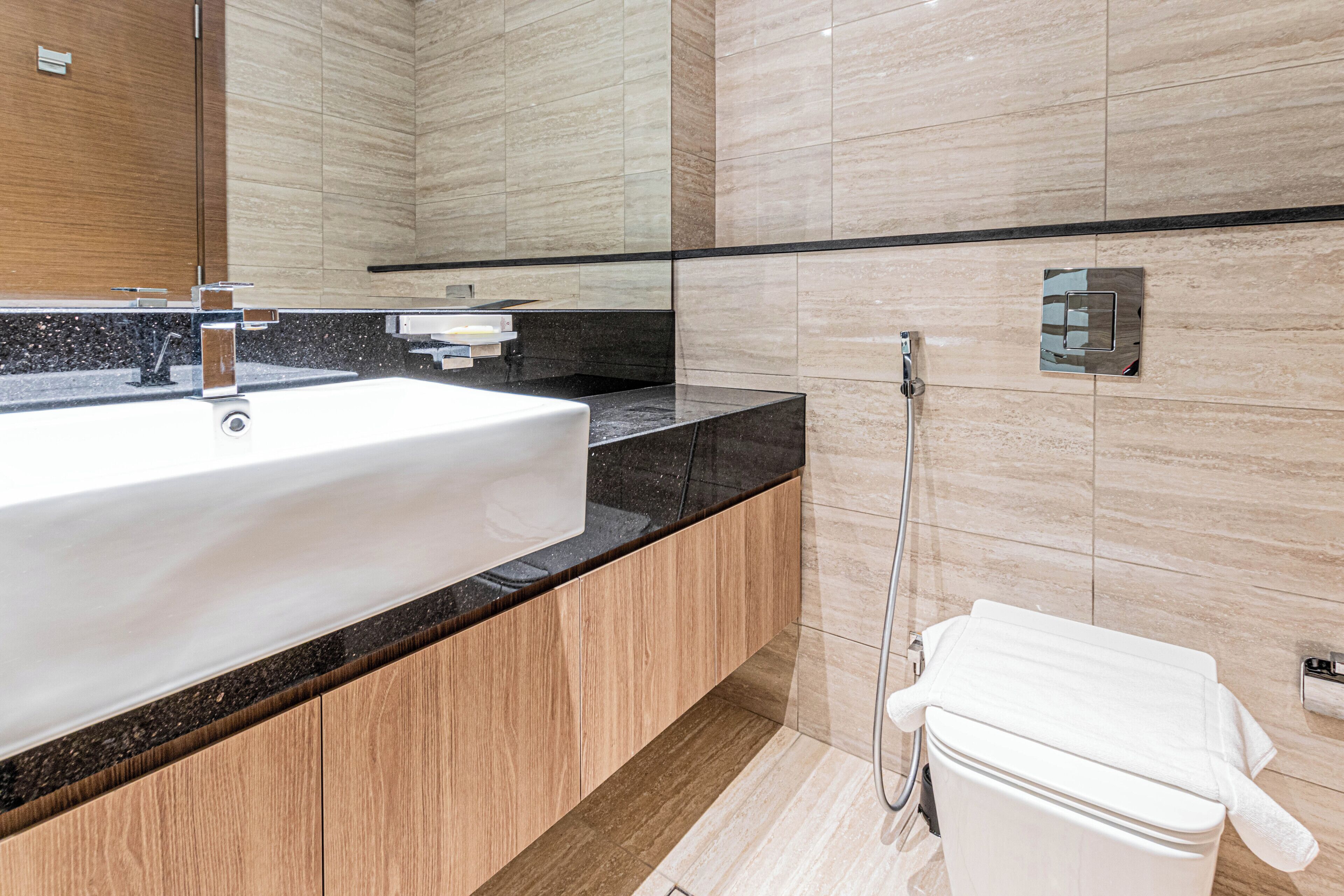 Een moderne badkamer met een groot wit wastafel, houten meubel en een douchecabine met glazen wanden.