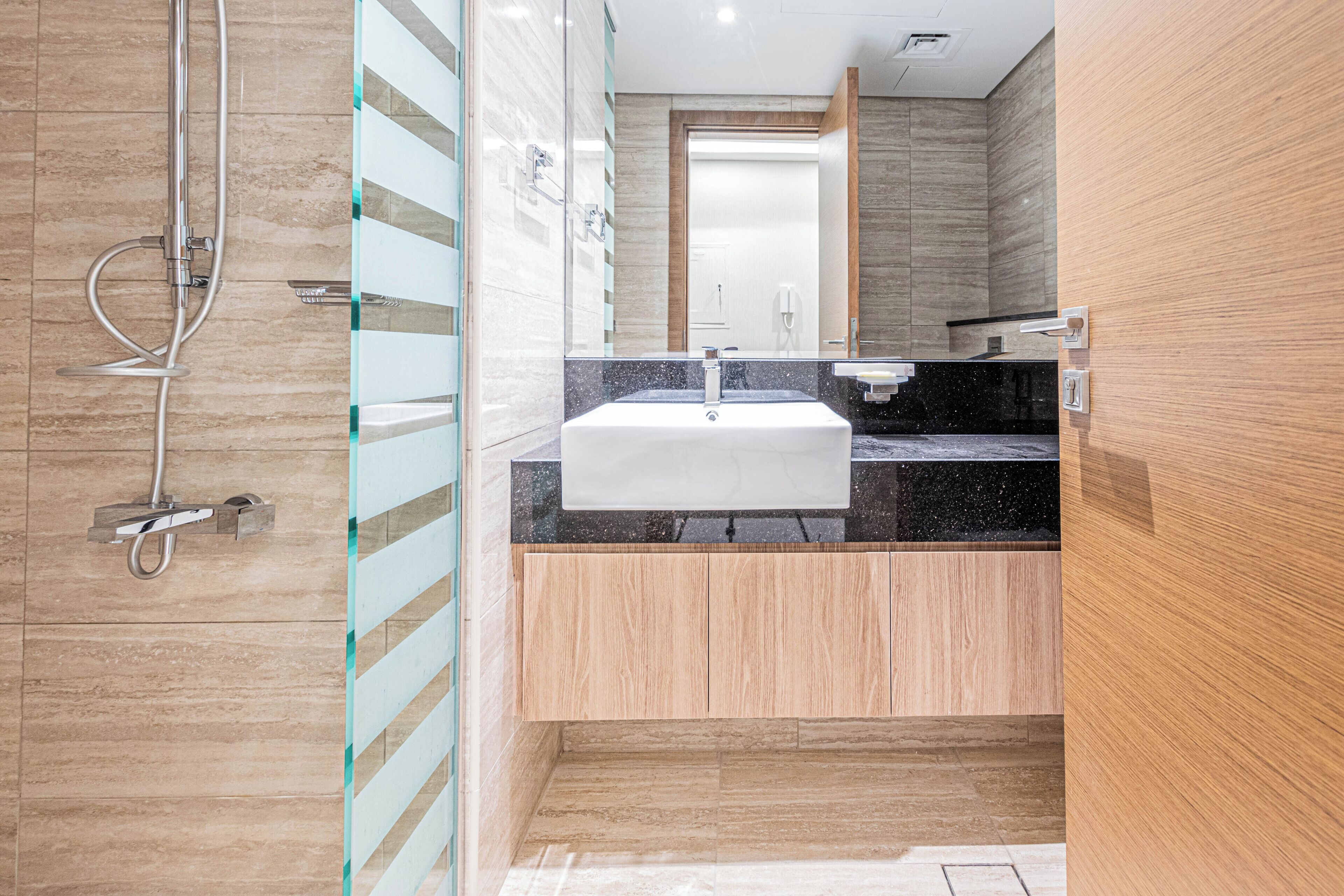 Un baño moderno con ducha, lavamanos y espejo.
