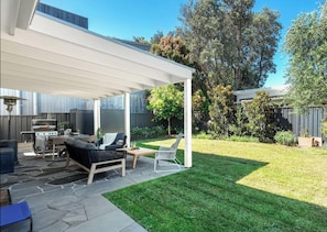 A covered patio with a grill, outdoor furniture, and a well-maintained lawn. - Sunshine Retreat – relaxing coastal retreat (Culburra Beach)