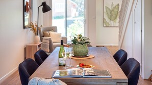 Een eettafel met een fles wijn, glazen, een bord eten en een boek.