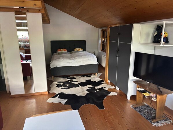 A bedroom with a bed, a television, a wardrobe, and a cowhide rug. - Gartenstudio "Belle Vue" by Interhome (Frutigen)