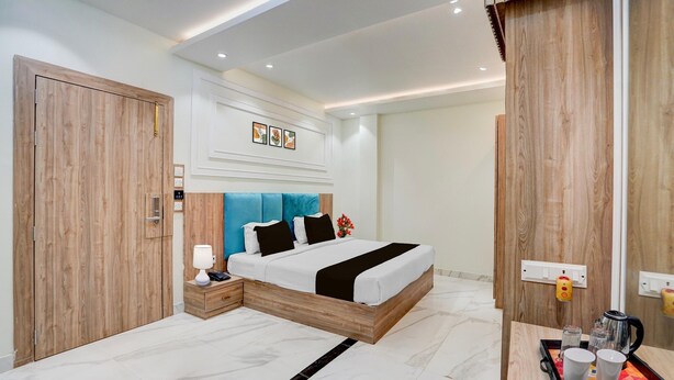 A modern hotel room with a wooden bed, bedside table, and a tray with cups and a coffee pot. - Super Deluxe Room Hotel Ballian's (Prayagraj)
