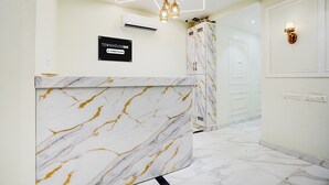 A reception desk with a marble design, a sign indicating a wheelchair-accessible room, and a modern light fixture. - Super Deluxe Room Hotel Ballian's (Prayagraj)