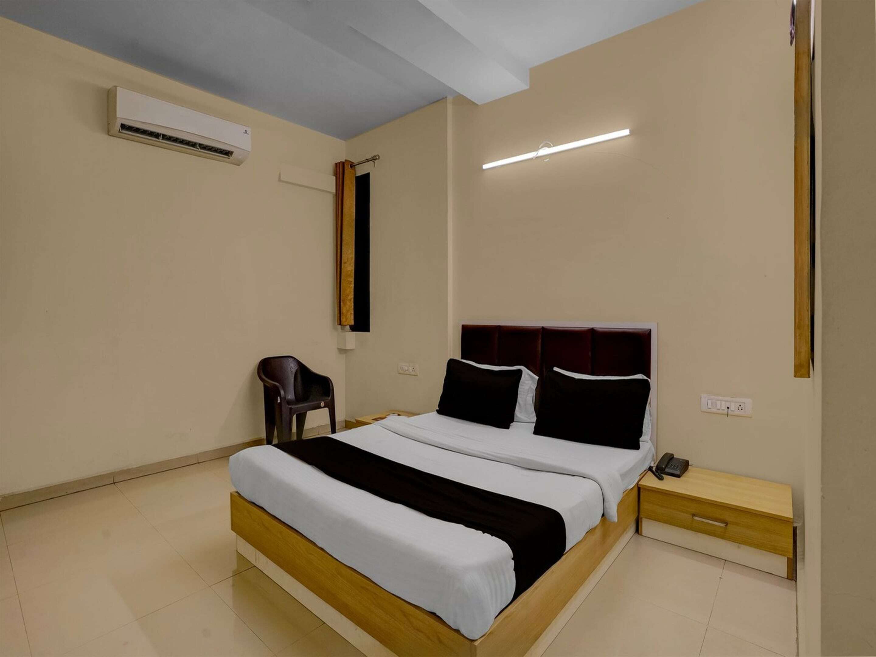 A bedroom with a bed, bedside table, and an air conditioning unit.