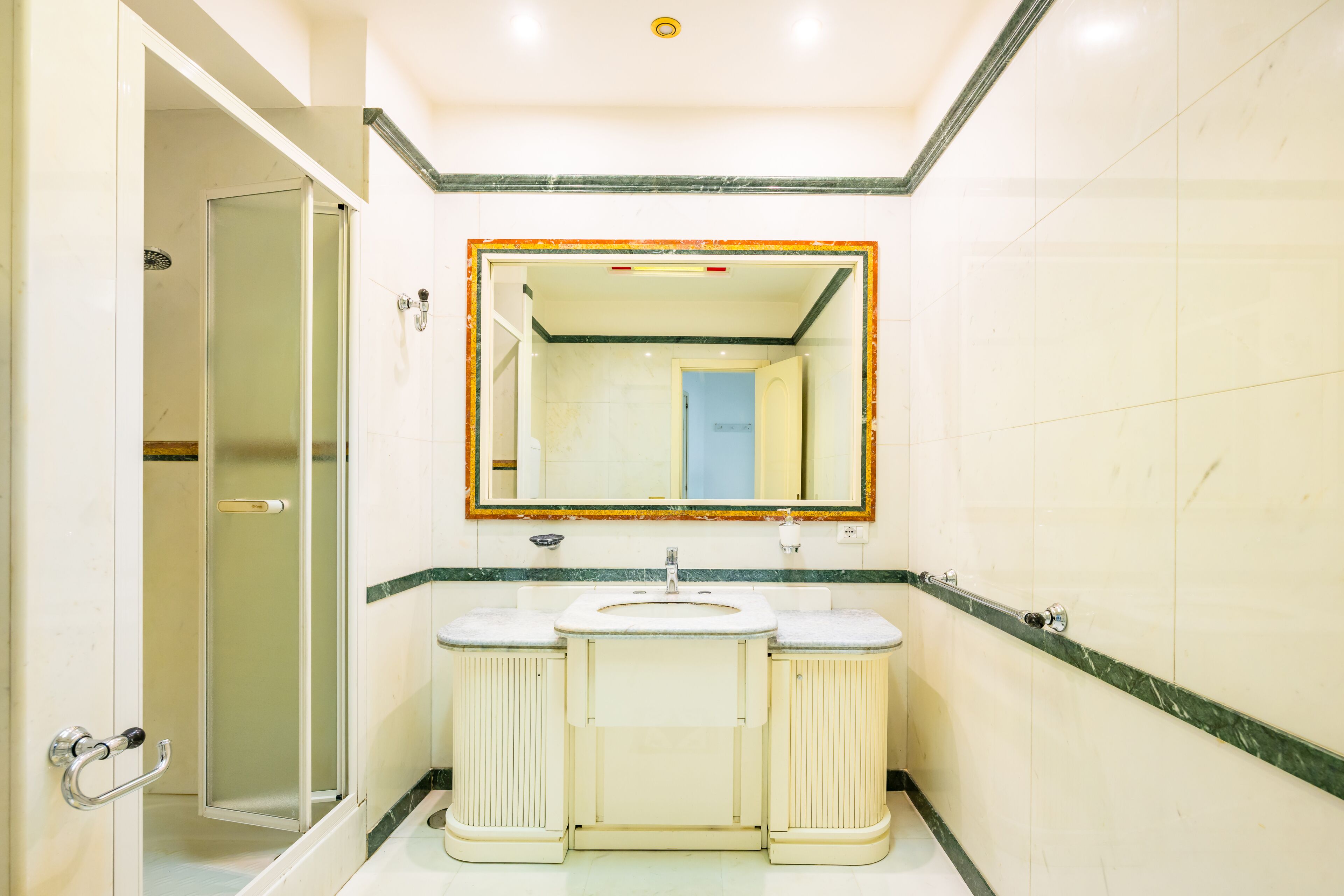 Ein Badezimmer mit Duschkabine, Waschbecken und Spiegel sowie Toilette.