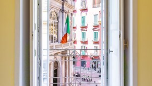 An open doorway leading to a balcony with a view of a building with balconies and a flag. - Luxury Toledo 22 (Naples)