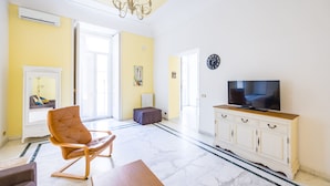 A living room with a TV, a fireplace, a chandelier, and a large window. - Luxury Toledo 22 (Naples)