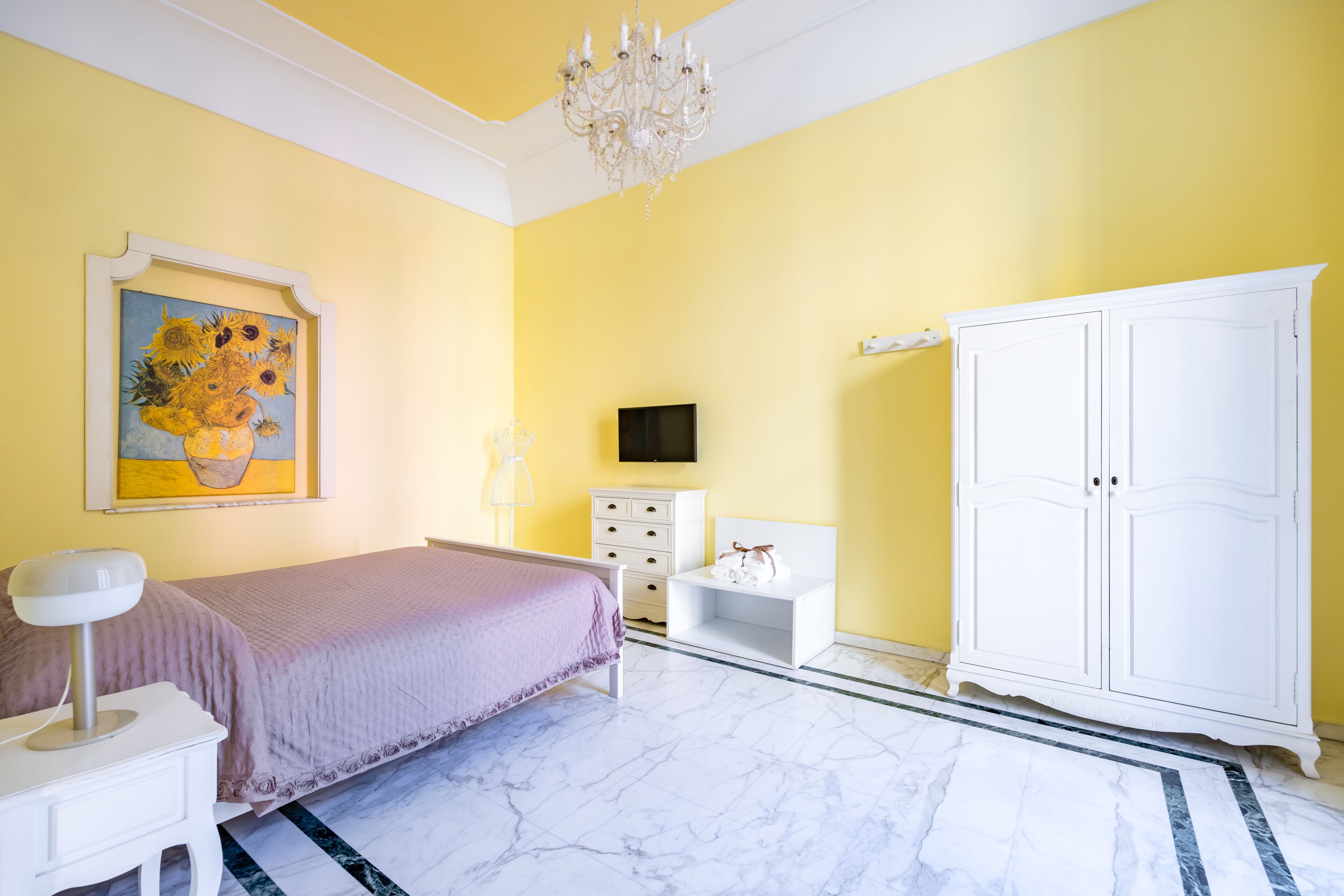 A bedroom with a bed, a dresser, a TV, a cabinet, and a painting on the wall.