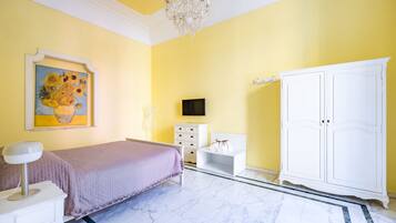 A bedroom with a bed, a dresser, a TV, a cabinet, and a painting on the wall.
