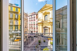 Blick durch ein Fenster auf eine Stadtstraße mit Gebäuden, einem gelben Bus und einer Fußgängerampel.