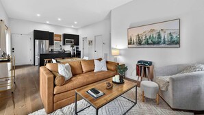 A modern living room with a brown leather sofa, a wooden coffee table, and a grey armchair.