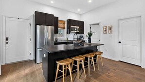 A modern kitchen with a central island, stainless steel appliances, and wooden stools.
