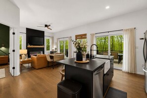 Un espacio de estar moderno con una isla de cocina, comedor y chimenea.