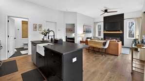 A modern kitchen with a central island, a dining area with a sofa, and a fireplace.