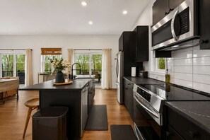 Cocina moderna con una isla central, electrodomésticos de acero inoxidable y vistas al exterior.