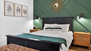A bedroom with a bed, nightstands, a dresser, and a wall-mounted mirror.